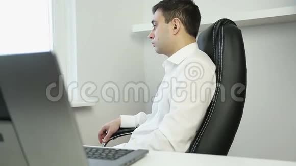 年轻的商人坐在办公椅上看着窗外视频的预览图