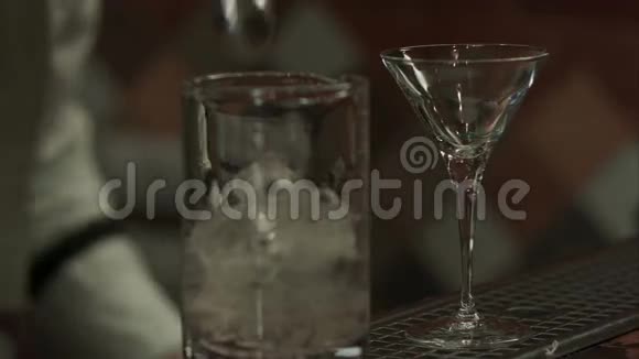 酒保在玻璃杯里加马提尼摇冰块然后倒入空玻璃杯视频的预览图