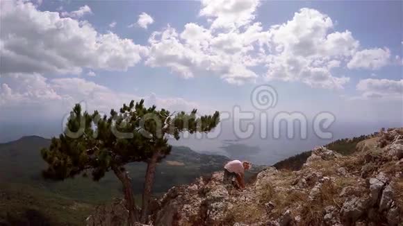 从山上的绿色森林和下面的城镇看美丽的风景小女孩坐在山的边缘视频的预览图
