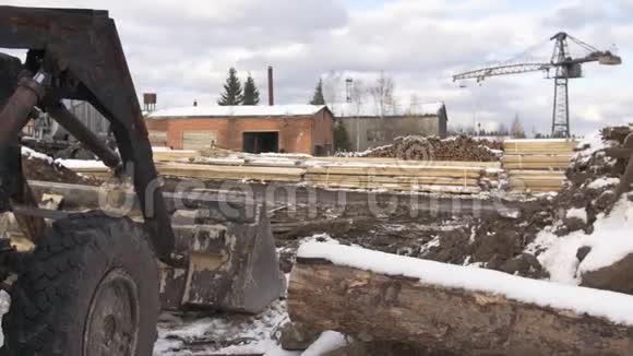 木工场的挖掘机储存了成堆覆盖着积雪的木材材料视频的预览图