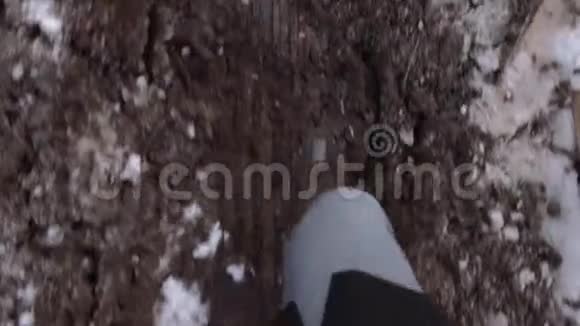 穿深色靴子的男子在冬天的肮脏道路上行走视频的预览图