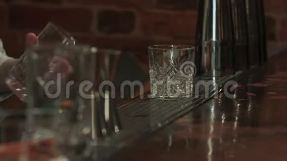酒吧里的酒吧老板手里拿着酒精鸡尾酒把冰和液体放到玻璃杯里视频的预览图