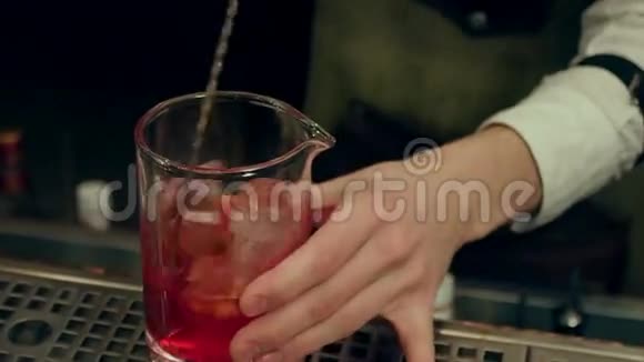 巴尔曼将红色斯普里茨开胃酒与冰块混合倒入空杯中视频的预览图