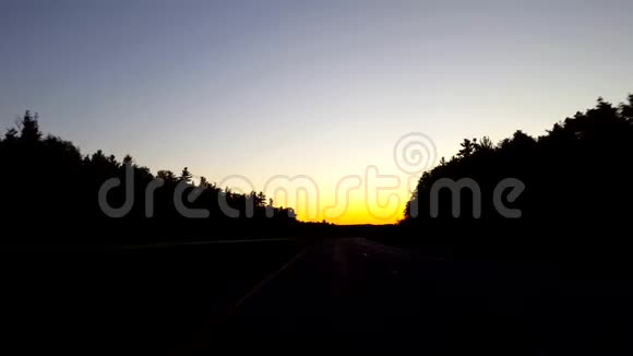 在日出期间驾驶乡村公路太阳清晨在地平线上升起时的驾驶视角视频的预览图