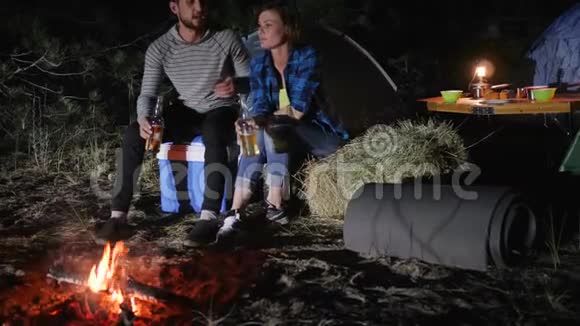浪漫的夜晚情人在森林里搭帐篷年轻夫妇在旅途中喝啤酒在大自然中搭帐篷旅游之旅视频的预览图
