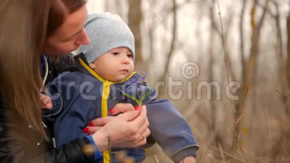在森林里的孩子带着妈妈的孩子在树林里玩妈妈和坐在树叶上的儿子玩孩子在视频的预览图
