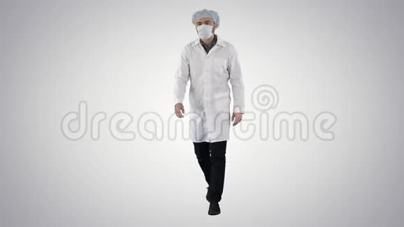戴着面具戴着医疗帽在渐变背景下行走的年轻男性医生视频的预览图