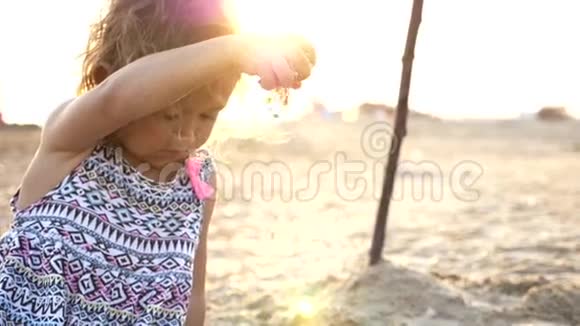 小女孩手里拿着沙子在海滩上让它再次掉下来视频的预览图