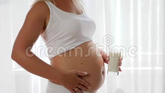 肚子大的妈妈拿着玻璃牛奶慢慢地伸出大拇指营养健康视频的预览图