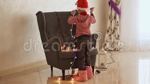 穿着圣诞老人衣服的孩子在椅子上分解燃烧的花环圣诞节的主题视频的预览图