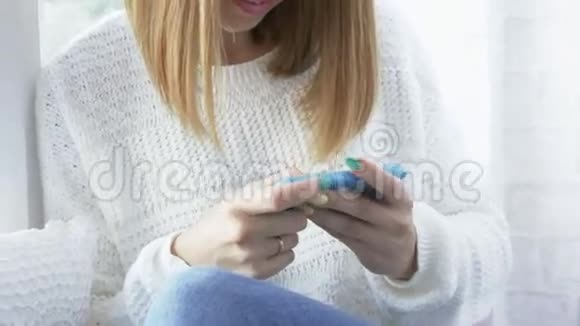 年轻女子坐在窗台上带着智能手机微笑的画像视频的预览图
