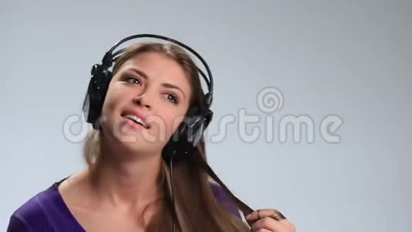 可爱的女孩带着耳机放松听音乐视频的预览图