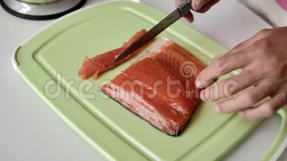 女性手用刀在浅绿色的砧板上切一片三文鱼视频的预览图