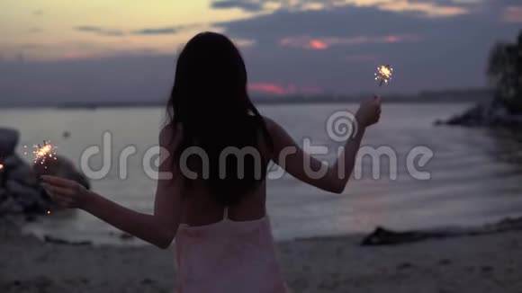 日落时为照相机摆姿势的女孩漂亮的年轻女人有火花慢动作视频的预览图