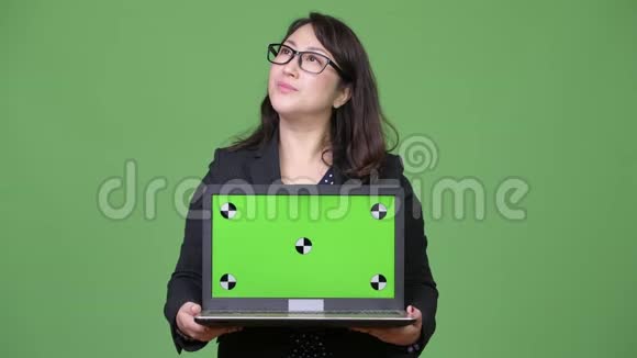 成熟漂亮的亚洲女商人绿色背景下展示笔记本电脑视频的预览图