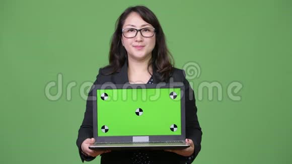 成熟漂亮的亚洲女商人绿色背景下展示笔记本电脑视频的预览图
