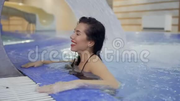 美丽的女人在游泳池的喷泉旁放松视频的预览图