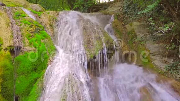 森林中的瀑布水流顺着苔藓的岩石和岩石流下来视频的预览图