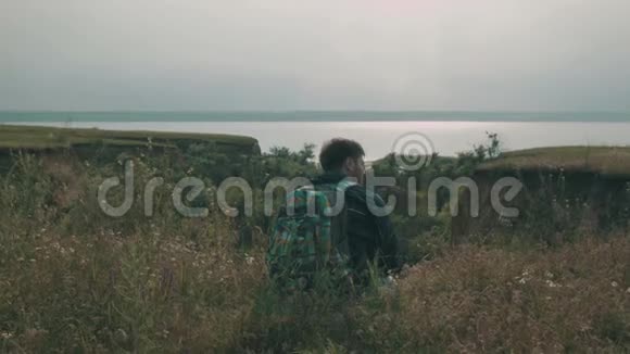 微笑的年轻探险家坐在绿色的草地上视频的预览图