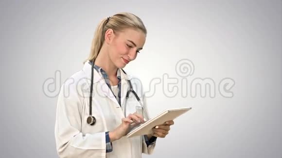 迷人的女医生听诊器微笑同时使用平板电脑的白色背景视频的预览图