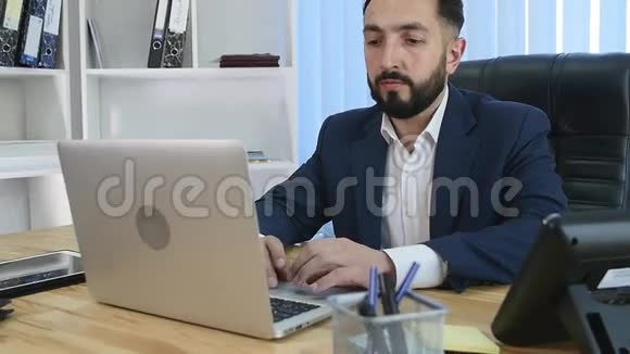 年轻的经理坐在明亮的办公室里的桌子上手提电脑视频的预览图