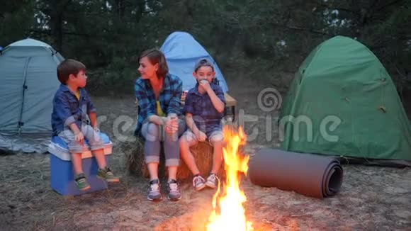 在营地里旅行母亲和两个孩子坐在贝尔菲旁边的稻草桶里母亲和孩子在附近交流视频的预览图