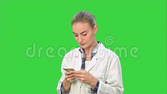 女医生使用现代智能手机发短信在绿色屏幕上微笑Chroma键视频的预览图