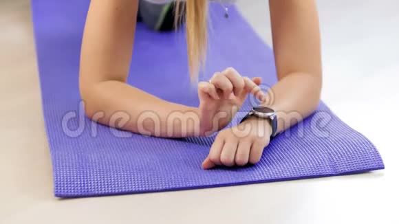在健身垫训练前年轻女子在智能手表上按下触摸屏的4K镜头视频的预览图