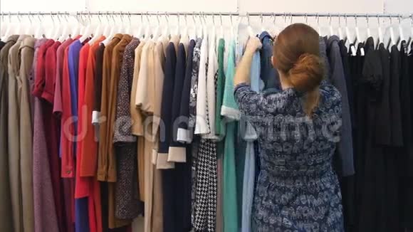 年轻的店主看着挂在栏杆上的时髦衣服在服装店里视频的预览图