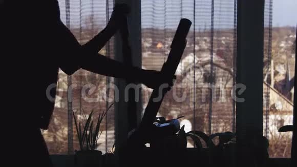 女性使用椭圆教练交叉教练在家里靠窗视频的预览图