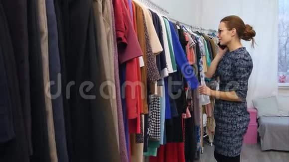 可爱的年轻女人在店里看衣服时用手机说话视频的预览图