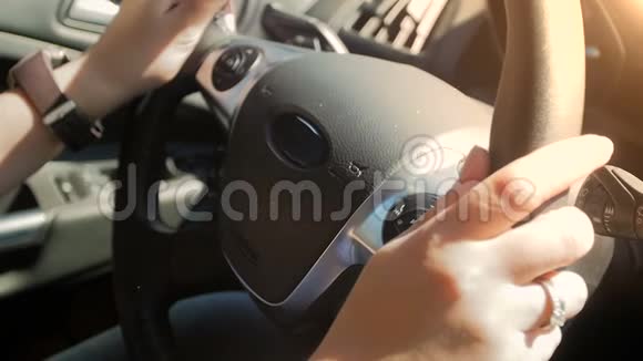 在阳光明媚的日子里年轻女子开车的特写慢镜头方向盘上的女性手视频的预览图