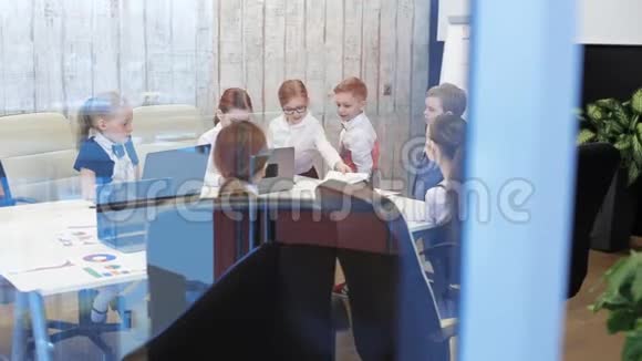 西装革履的商务儿童正坐在办公室的桌子旁视频的预览图