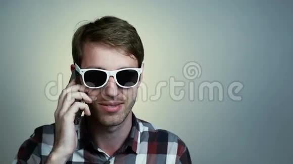 戴眼镜的年轻人在用手机说话视频的预览图