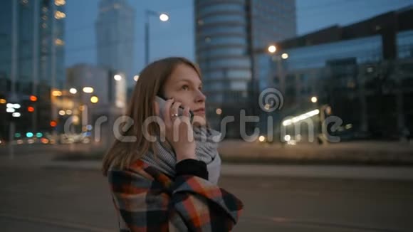 年轻女子正在电话交谈在夜间现代城市中心散步视频的预览图