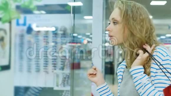 带着袋子在商店橱窗里购物的年轻女子视频的预览图