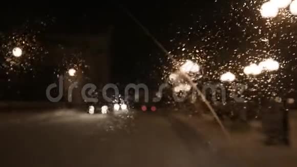 司机在一个城市的雨夜开车从里面看录像雨中汽车挡风玻璃上的景色视频的预览图