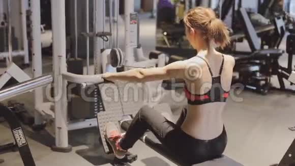 运动中的年轻女性在健身房的三头肌模拟器中进行健身锻炼视频的预览图