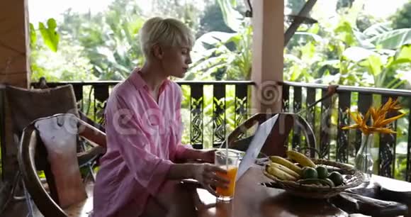 小女孩用笔记本电脑坐在夏日露台的桌子旁美女在户外上网聊天视频的预览图