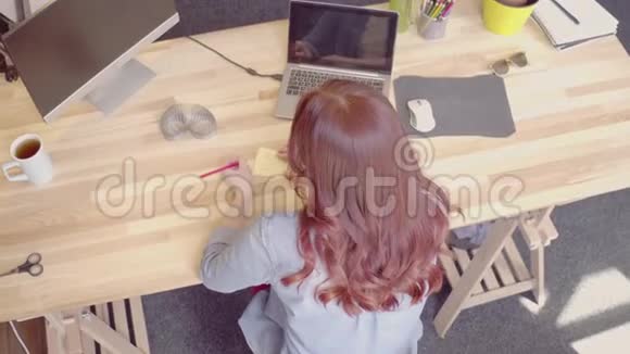 在木桌上工作的狐狸年轻女商人的俯视图视频的预览图