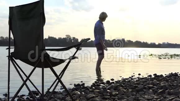 光着脚站在河岸边的水中在斯隆莫掷石头视频的预览图