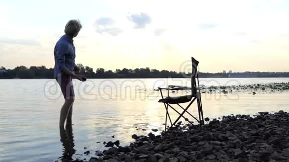 光着脚站在河岸边的水中在斯隆的石头上视频的预览图