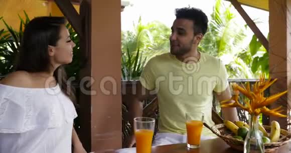 快乐的情侣坐在夏日的露台上聊天早餐时男女交流视频的预览图