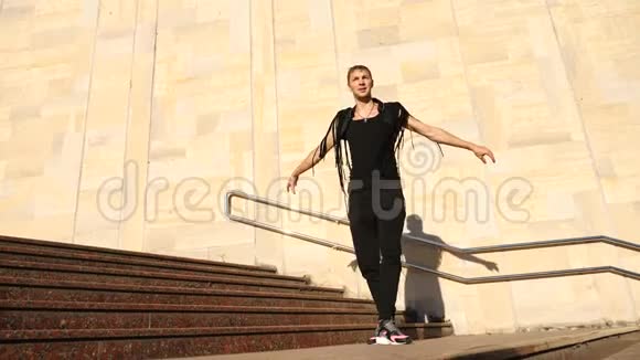 一个年轻快乐的家伙跳着现代芭蕾舞在街上的楼梯上摇摇晃晃的慢分子视频的预览图