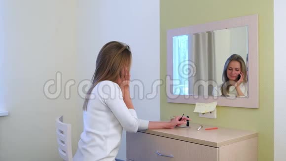 年轻女子在酒店镜子前化妆时打电话视频的预览图