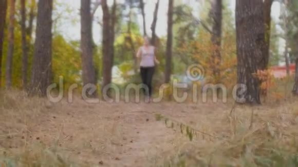 快乐的年轻女子在森林慢跑和拍摄自拍棒视频视频的预览图