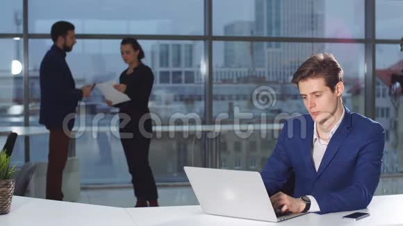 年轻有魅力的商人在办公桌上工作的肖像在办公室里使用笔记本电脑视频的预览图
