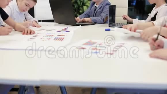 西装革履的商务儿童正坐在办公室的餐桌旁视频的预览图
