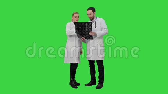 医生检查X射线并讨论在绿色屏幕上手术的成功结果Chroma键视频的预览图
