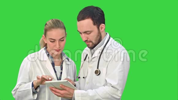 两位专家医学专业人士讨论了一种治疗病人的方法同时使用他们的平板电脑在绿色屏幕上Chroma键视频的预览图